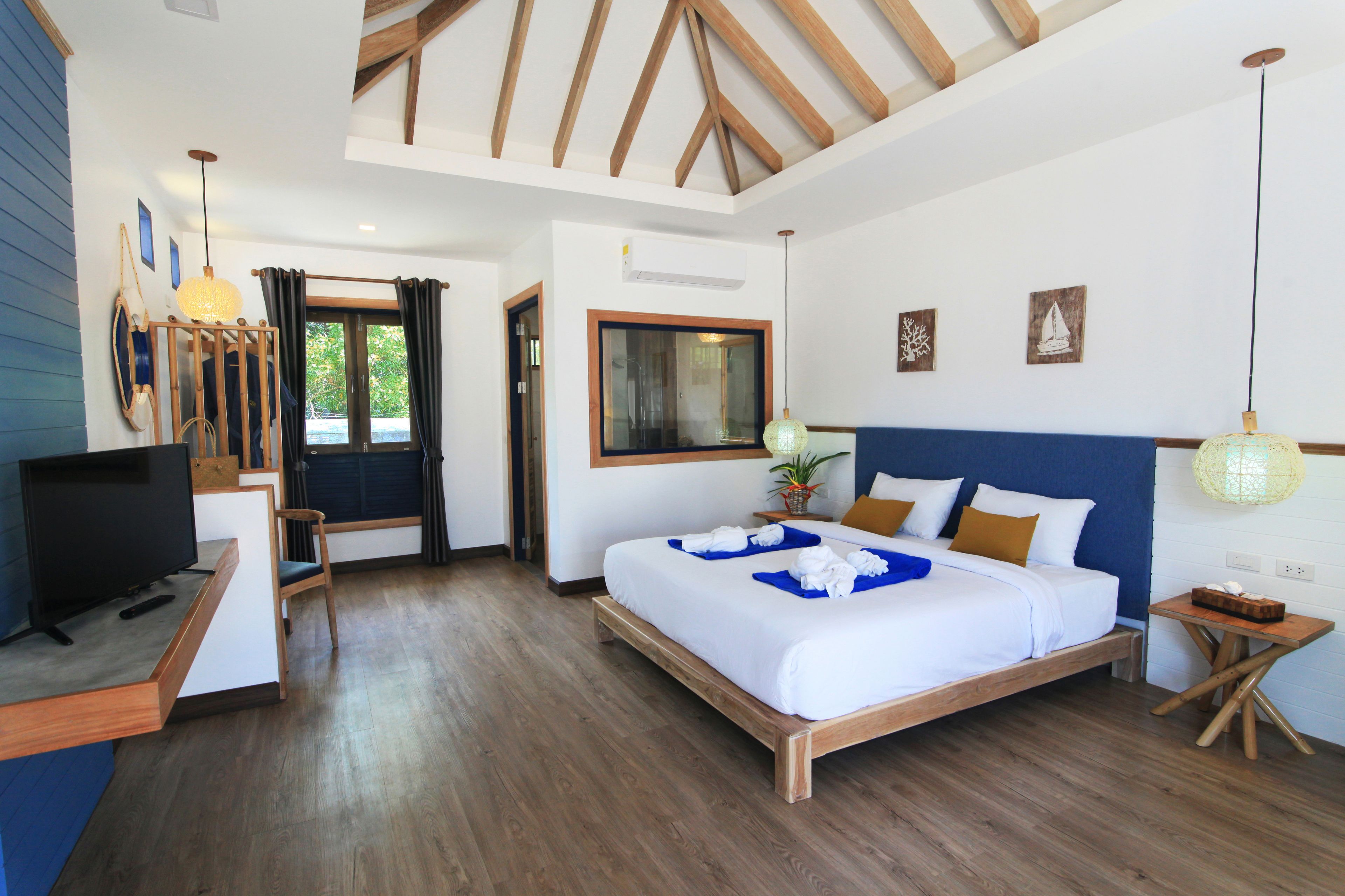 Una habitación de hotel moderna con techo de madera, una cama grande, un televisor y un escritorio.