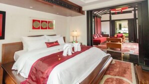 Una habitación de hotel con una cama grande, un cabecero de madera, una pared de acento roja y vistas al área de estar exterior.