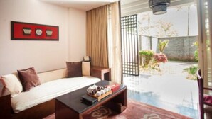 Habitación de hotel con cama, una mesita de café y vistas a un jardín y un estanque.