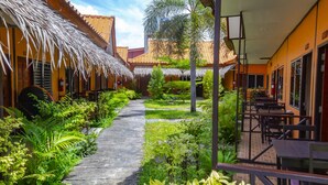 A courtyard with a thatched-roof structure, a paved walkway, and outdoor seating. - Baan Kasirin Resort Pattaya Beach (Koh Lipe)