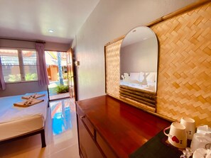 A hotel room with a bed, a wooden desk, a mirror, and a view of the outside. - Baan Kasirin Resort Pattaya Beach (Koh Lipe)
