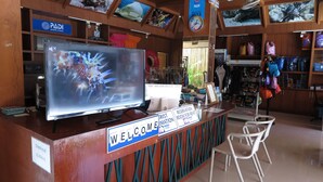 A reception desk with a 'Welcome' sign, a television displaying a colorful image, and a 'Check out' sign indicating 11:00 A.M. - Baan Kasirin Resort Pattaya Beach (Koh Lipe)