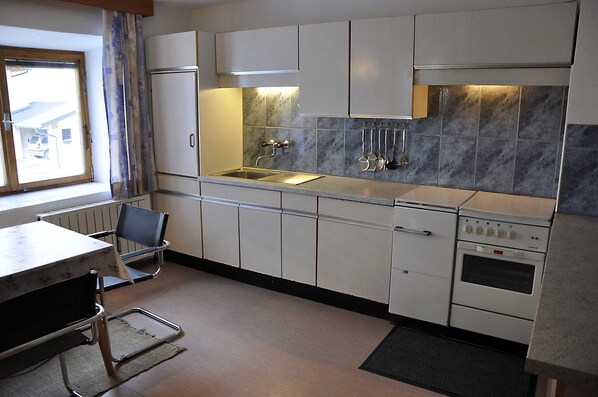 A compact kitchen with a sink, stove, and cabinets. - Vacation apartment 1 - Schweizerhof (Wenns)