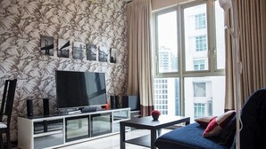 A modern living room with a large flat-screen TV, a sofa, a coffee table, and a patterned wallpaper. - Marc B20-09 by SYNC (Kuala Lumpur)