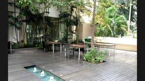 An outdoor patio with wooden flooring, a rectangular water feature, and tables and chairs. - Marc B20-09 by SYNC (Kuala Lumpur)
