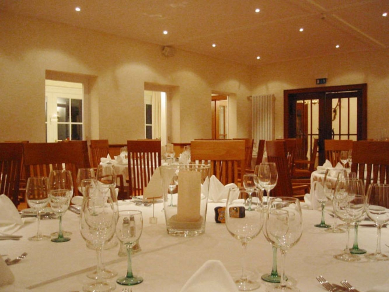 Un salón de banquetes con mesas dispuestas para un evento formal, con cristalería y manteles blancos.