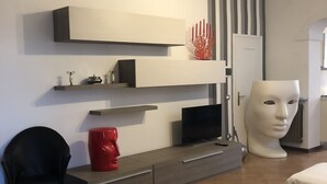 A modern living room with a flat-screen TV, a red sculpture, and a white bust on a pedestal. - Dimora Del Podestà (Castell'Arquato)