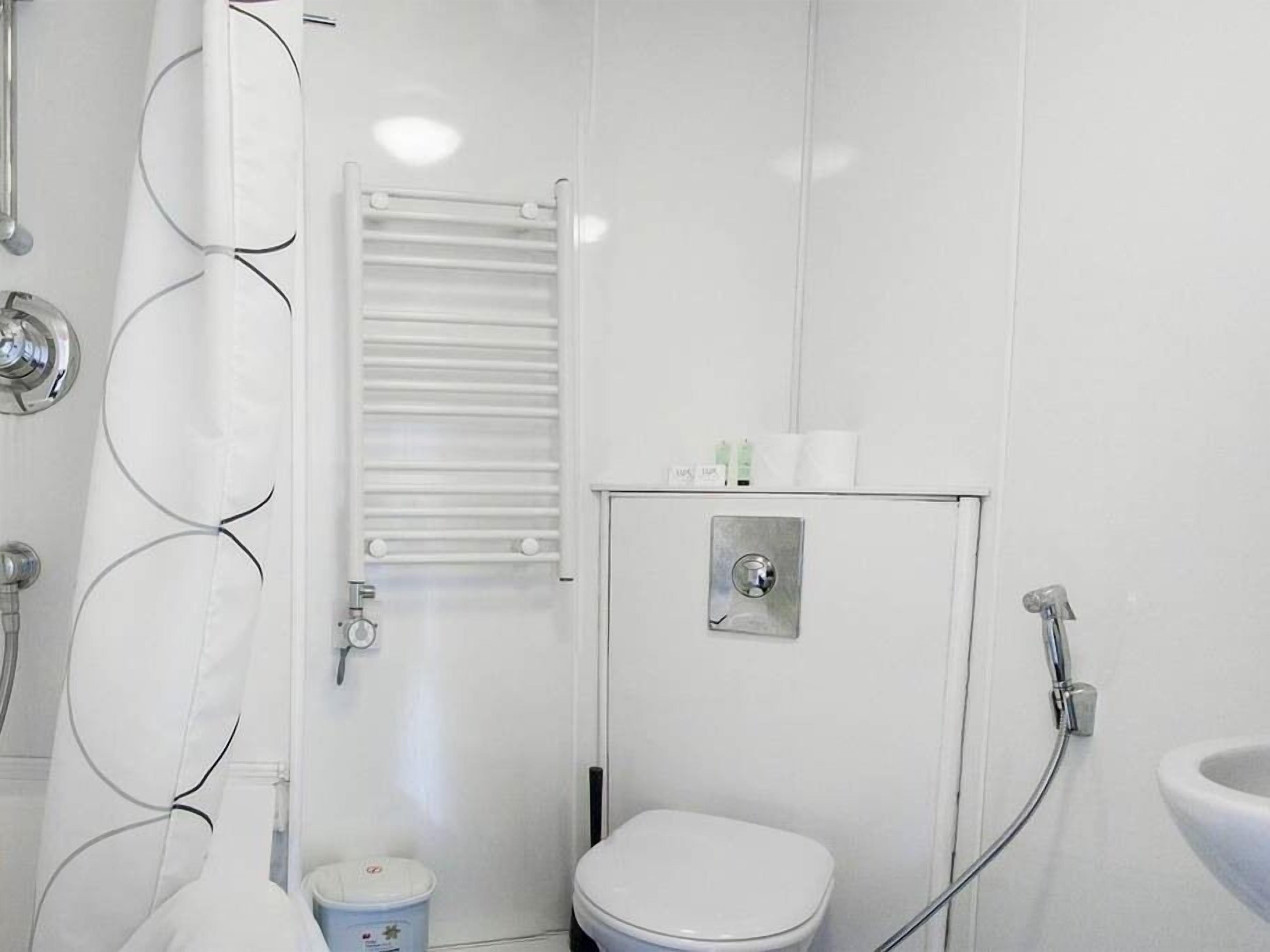 A bathroom with a white toilet, a shower area, and a sink.