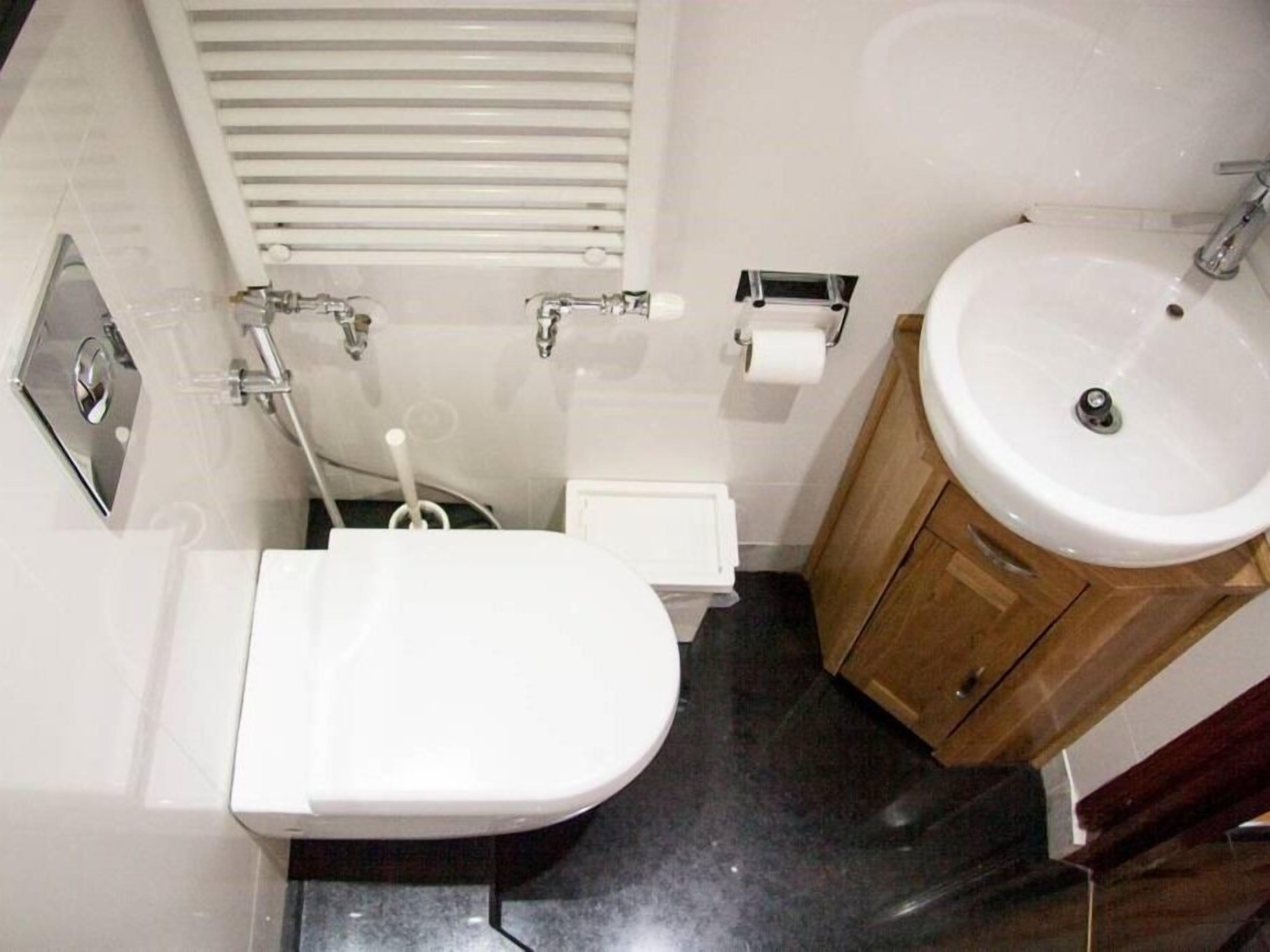 Casa de banho compacta com sanita, lavatório e chuveiro.