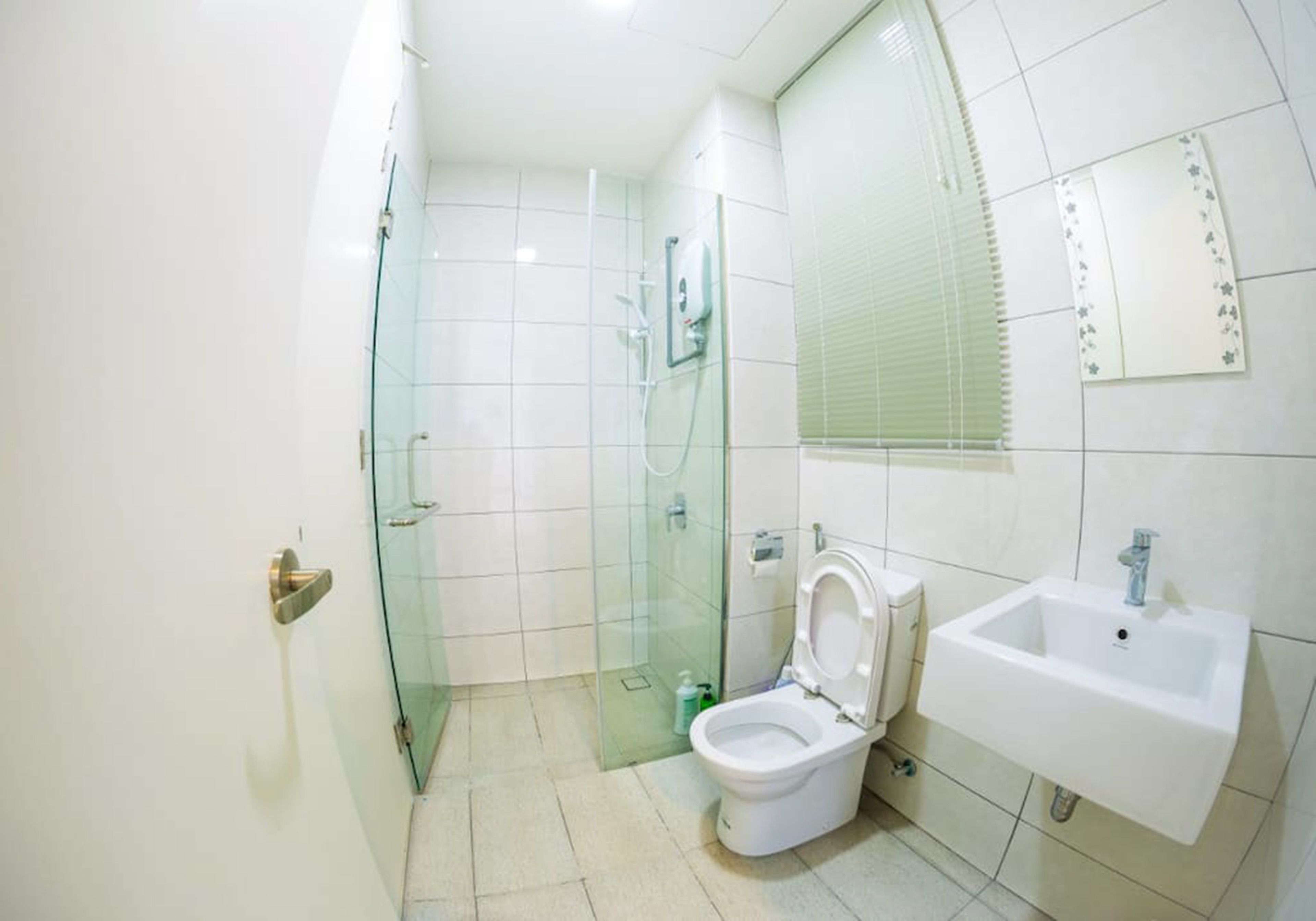 Une salle de bain moderne avec une douche à parois de verre, des toilettes blanches et un lavabo surmonté d’un miroir.