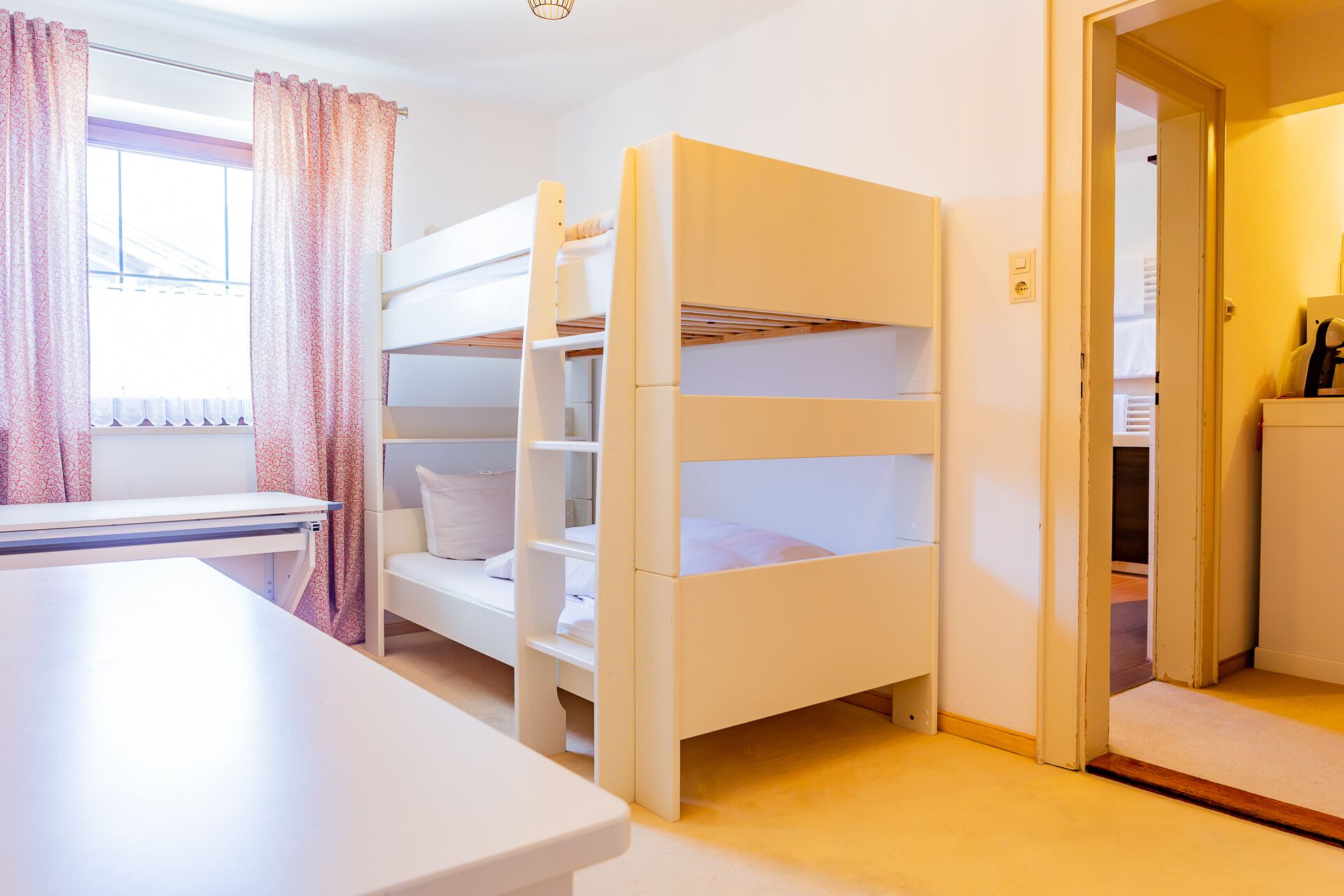 Una habitación con literas, un escritorio y una ventana con cortinas.
