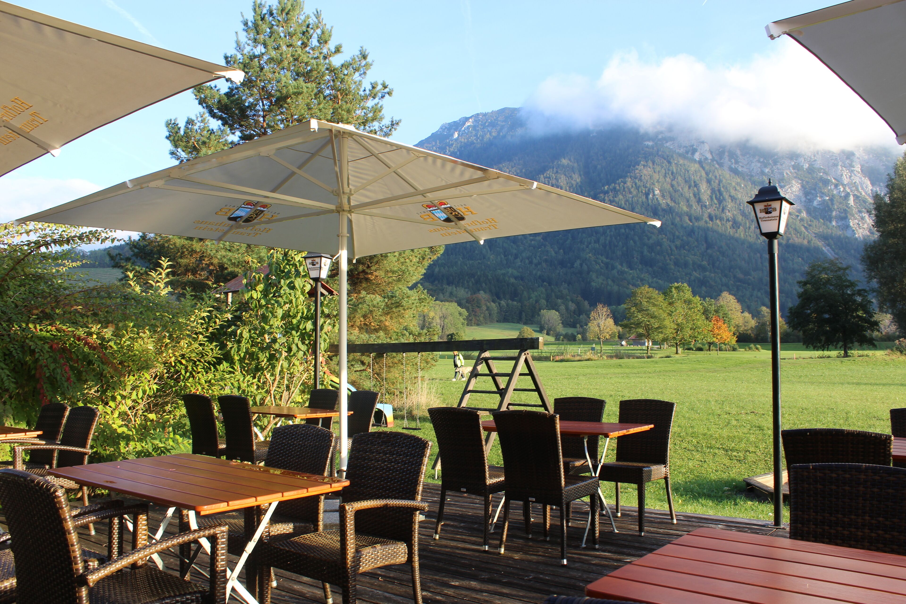 An outdoor patio with tables and chairs, a ladder, and a mountain view in the background.