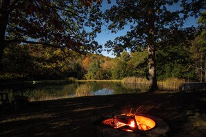 Un fuoco da campo in una zona boschiva, con un lago sullo sfondo.