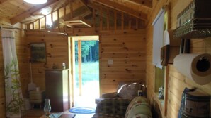 L’intérieur d’un chalet accueillant, avec un plancher en bois, un canapé, une table et une grande fenêtre.