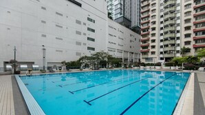 Piscina com água azul cristalina, rodeada por um deck revestido de azulejos.