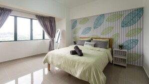Quarto com cama, mesa de cabeceira, janela com cortinas e parede com estampas de folhas.