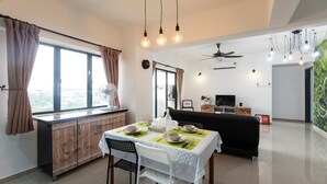 Uma sala de estar moderna com área de jantar, um sofá preto, televisão e ventilador de teto.