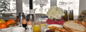 A breakfast table with eggs, bread, and a coffee maker. - Hotel Tirol (Sallent de Gallego)