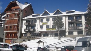 Un hôtel à plusieurs étages, doté de balcons et d’une enseigne indiquant la présence d’un restaurant.