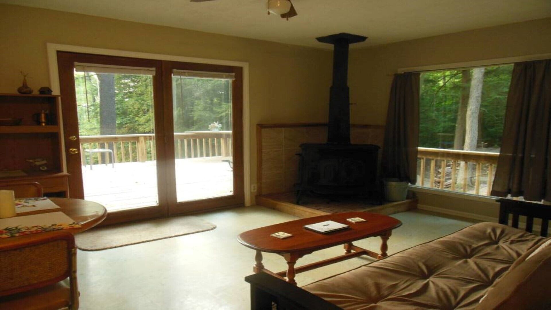 A cozy living room with a fireplace, a sofa, a table, and a view of the outdoors.