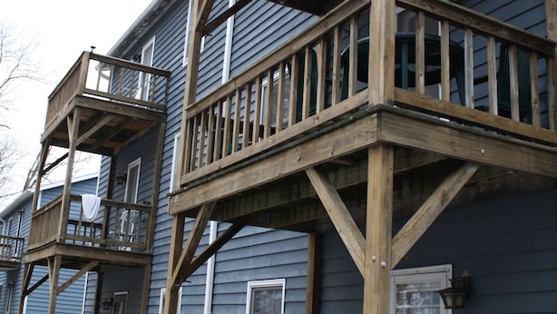 A two-story house with a wooden deck and a blue chair. - Great Mountain Get Away (Boone)