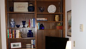 A corner room with a built-in wooden entertainment center, bookshelves, a flat-screen TV, and a small table with a lamp. - Great Mountain Get Away (Boone)