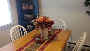 A dining table with a floral centerpiece, white chairs, and a table runner. - Great Mountain Get Away (Boone)