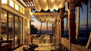 A restaurant with outdoor seating, a view of the ocean, and a sunset. - Dorado Beach a Ritz Carlton Reserve (Dorado)