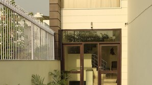 A modern building with a glass door entrance, potted plants, and a metal fence. - Treehouse Neo Casa-Unit of Neo Residency (Gurugram)