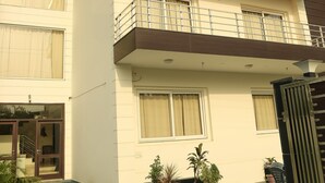 A modern two-story building with balconies, large windows, and potted plants. - Treehouse Neo Casa-Unit of Neo Residency (Gurugram)