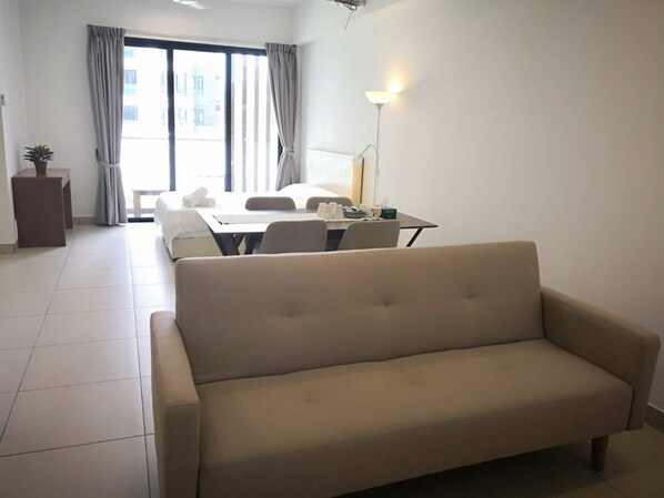 A modern living room with a sofa, a dining table, and a lamp.