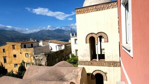A narrow alleyway with a building featuring a dome and arched windows, leading to a view of mountains and a clear sky. - Santa Lucia B&B (Gaeta)