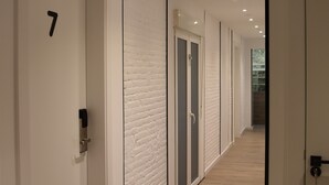 A modern hallway with white walls, a wooden floor, and doors numbered 7 and 8. - Casp Green House (Barcelona)
