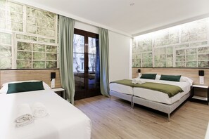 A hotel room with a large bed, a smaller bed, a wooden floor, and a view through the window. - Casp Green House (Barcelona)