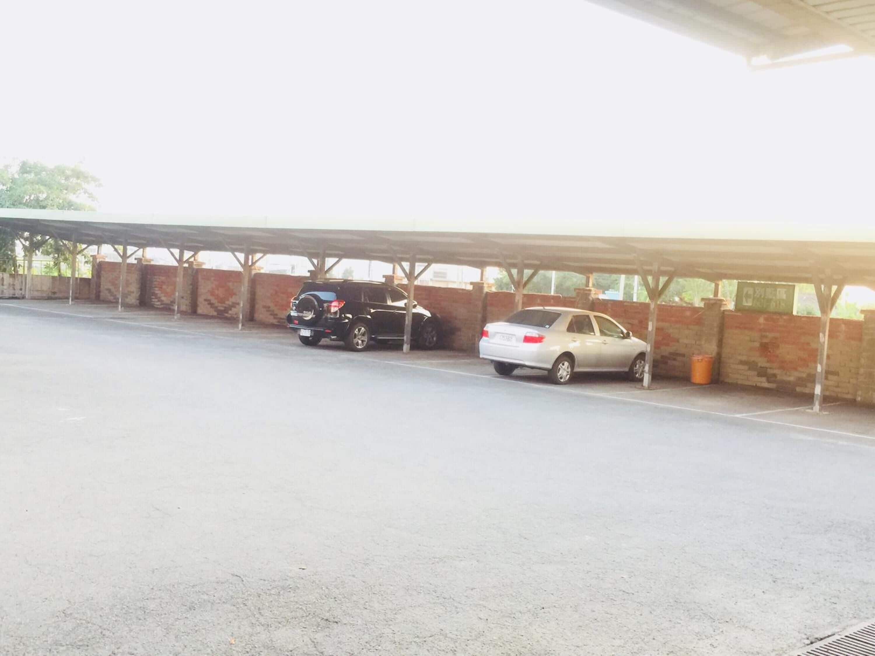 Un área de estacionamiento techada con dos coches estacionados bajo una protección.