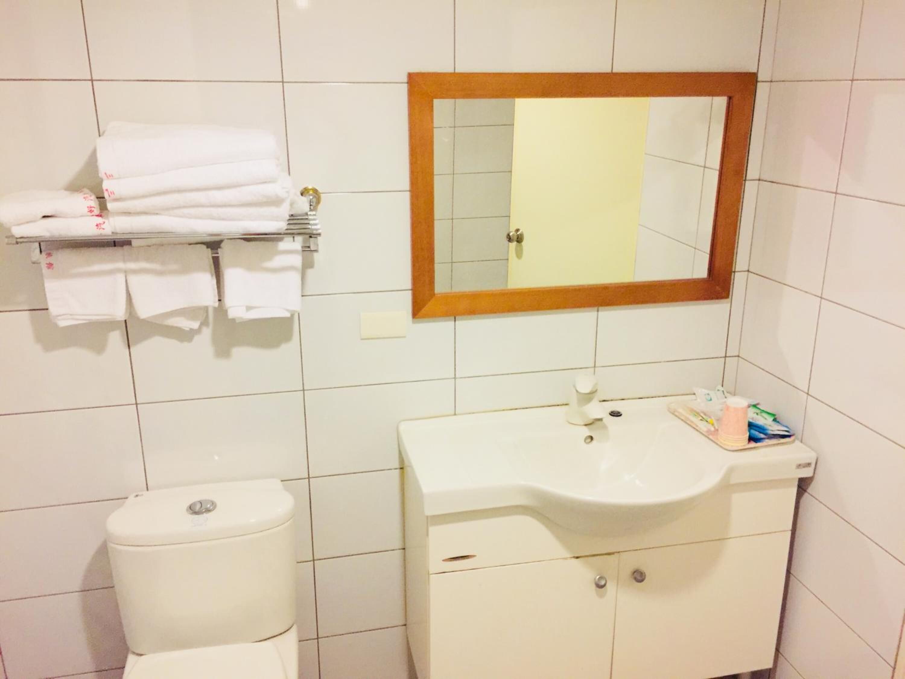 Une salle de bain avec des toilettes, un lavabo et un miroir.