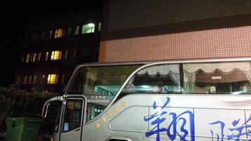 Un autobús estacionado de noche con texto azul en la carrocería.