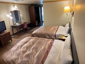 Une chambre d’hôtel avec deux lits, un bureau avec une chaise, une télévision et un miroir.