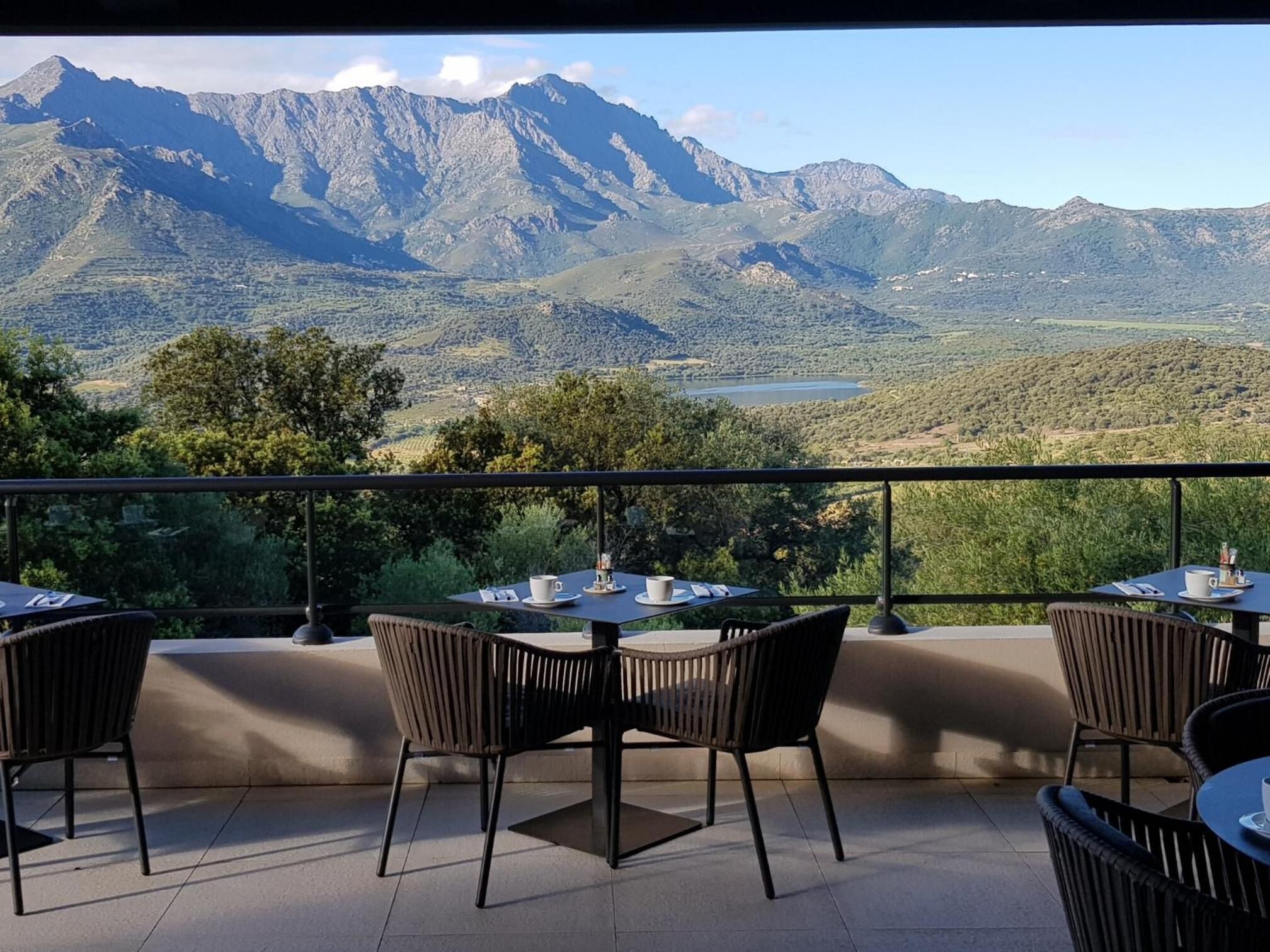 A terrace with tables and chairs overlooking a mountainous landscape.