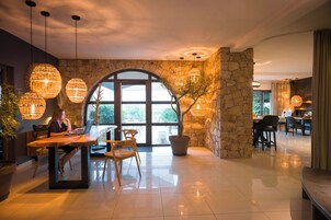 Un vestíbulo amplio con pared de piedra, ventanas grandes y luminarias modernas.
