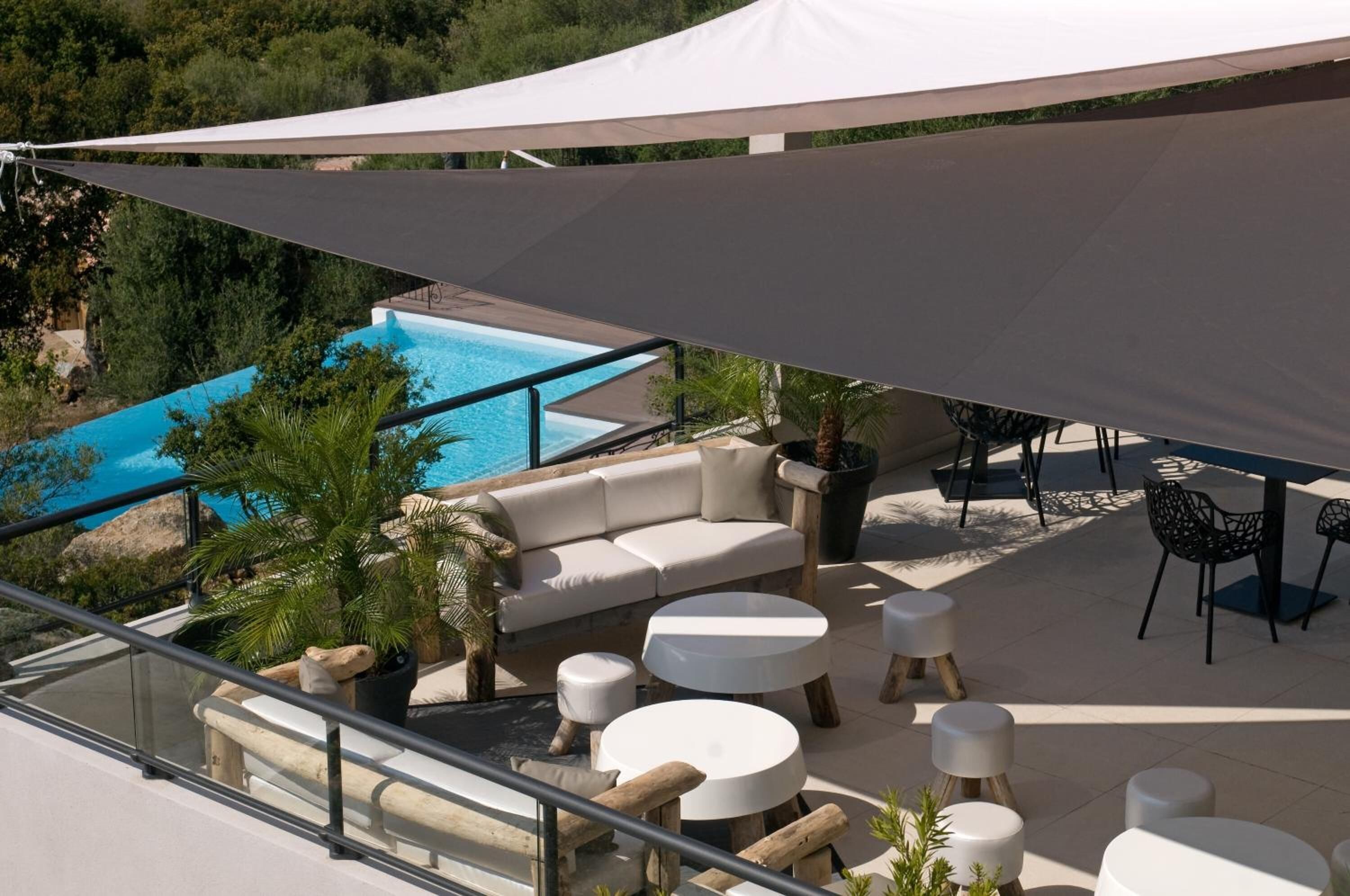 An outdoor patio with a pool, white furniture, and a large canopy.