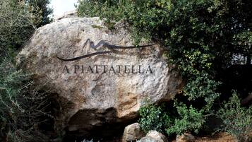 A large rock with the inscription "A PIAFATTELLA" surrounded by greenery.