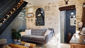 A cozy living room with a grey sofa, wooden coffee table, and a stone wall. - Secret Pyrénées (Lasseube)