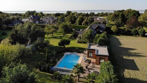 A residential area with a swimming pool, houses, and a view of the sea. - La Griotte Chambre D'hotes (Honfleur)