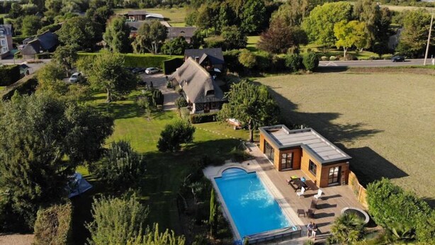 A residential area with a swimming pool, houses, and a view of the sea. - La Griotte Chambre D'hotes (Honfleur)