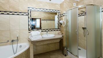 Un baño moderno con bañera, lavamanos y cabina de ducha con mampara de vidrio.