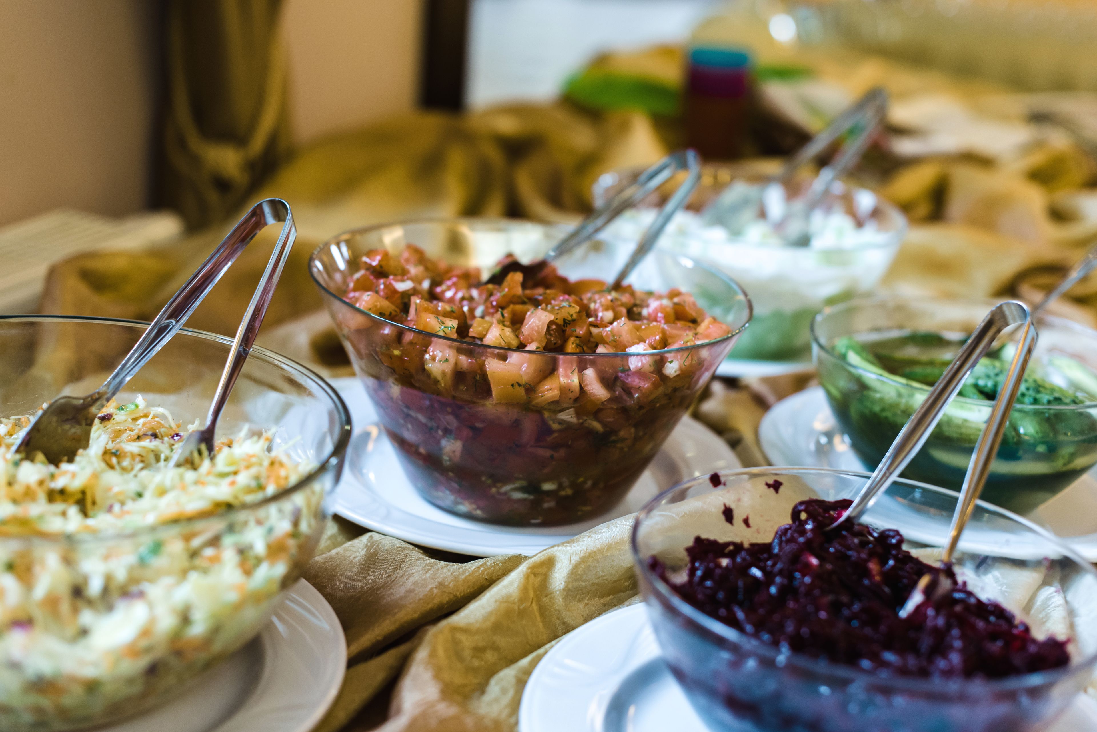 A table with various dishes, including a salad, a coleslaw, and a bowl of red berries.
