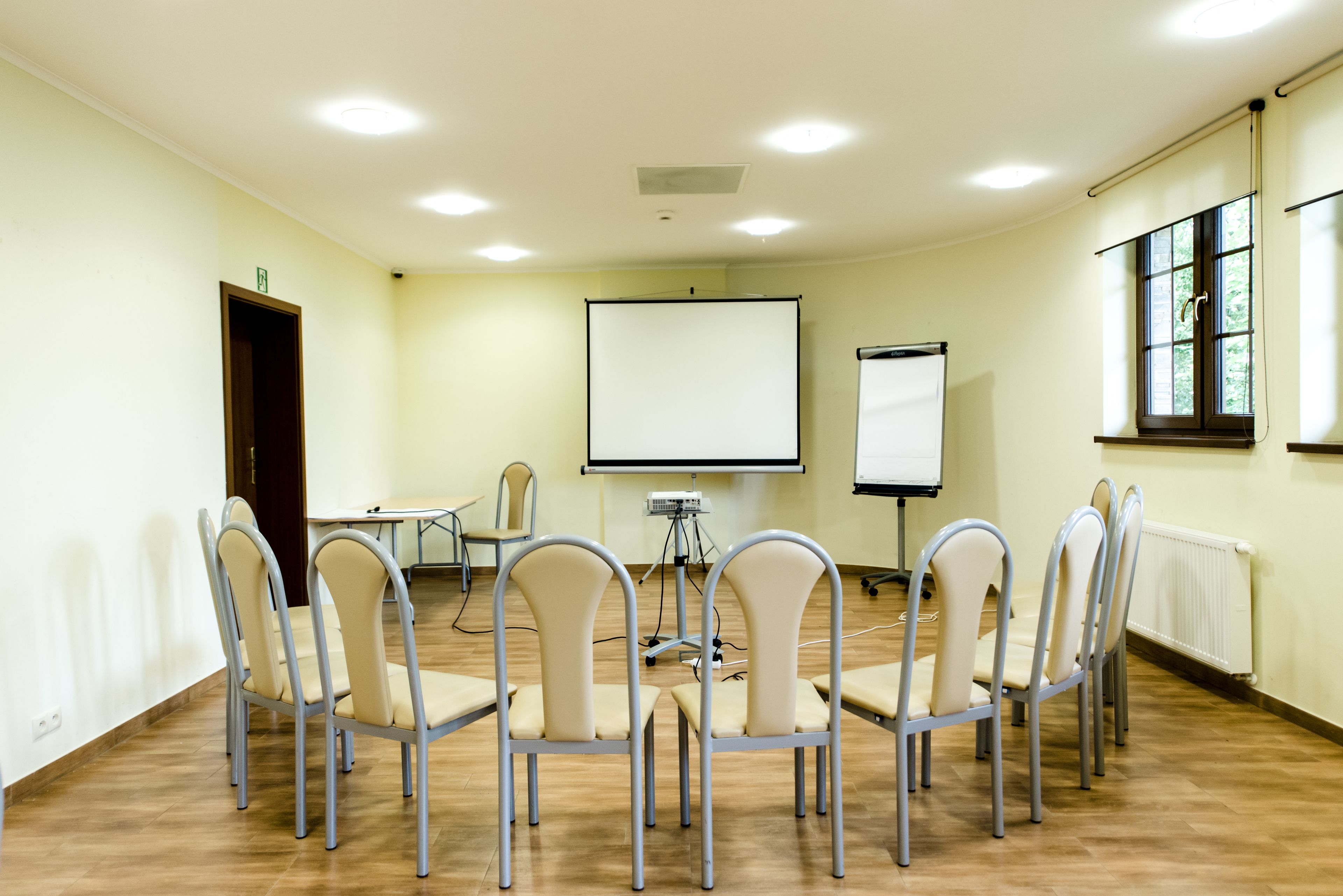 A conference room with a whiteboard, projector, and several chairs arranged in a semi-circle.