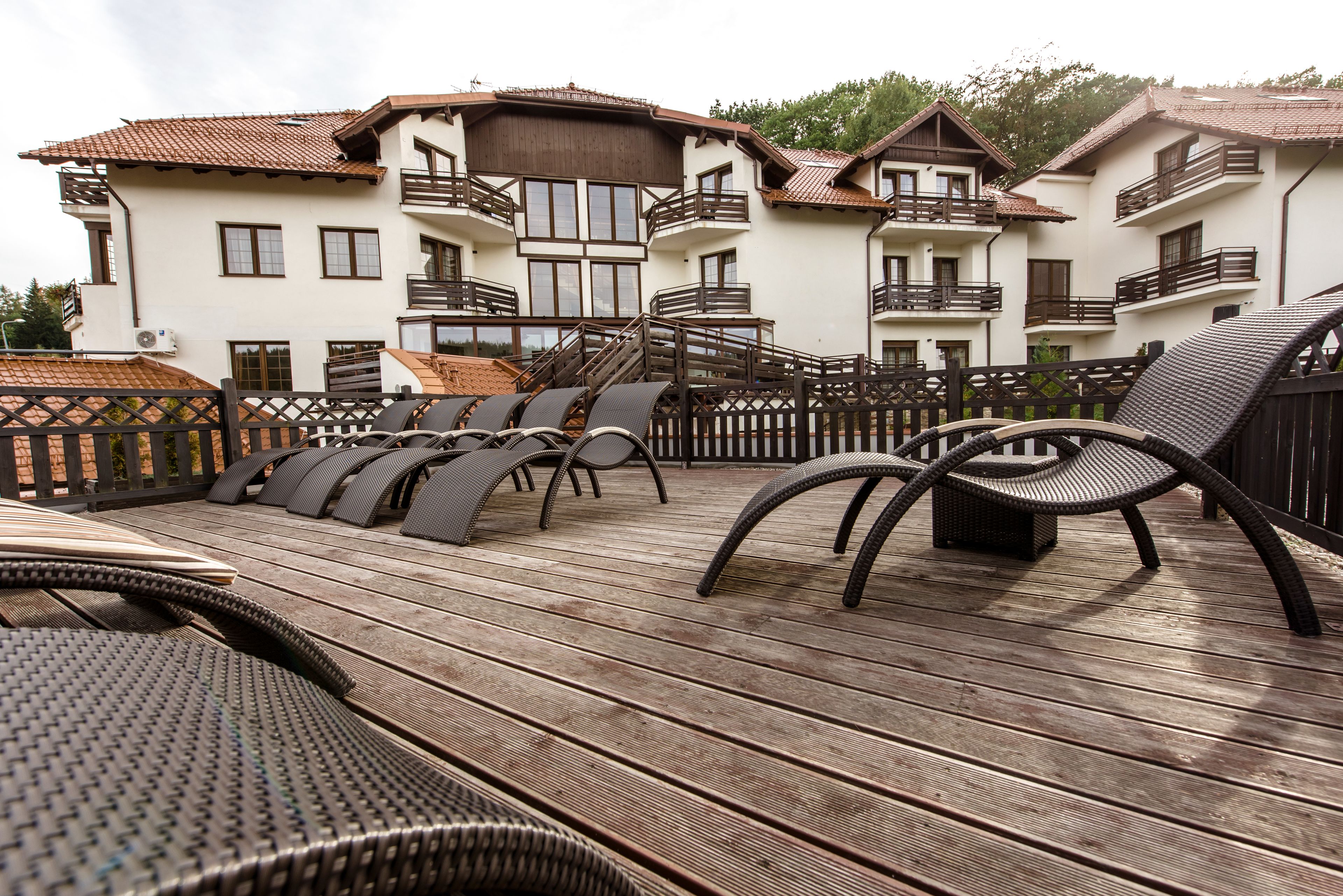 A wooden deck with outdoor furniture, a pool, and a building with balconies.