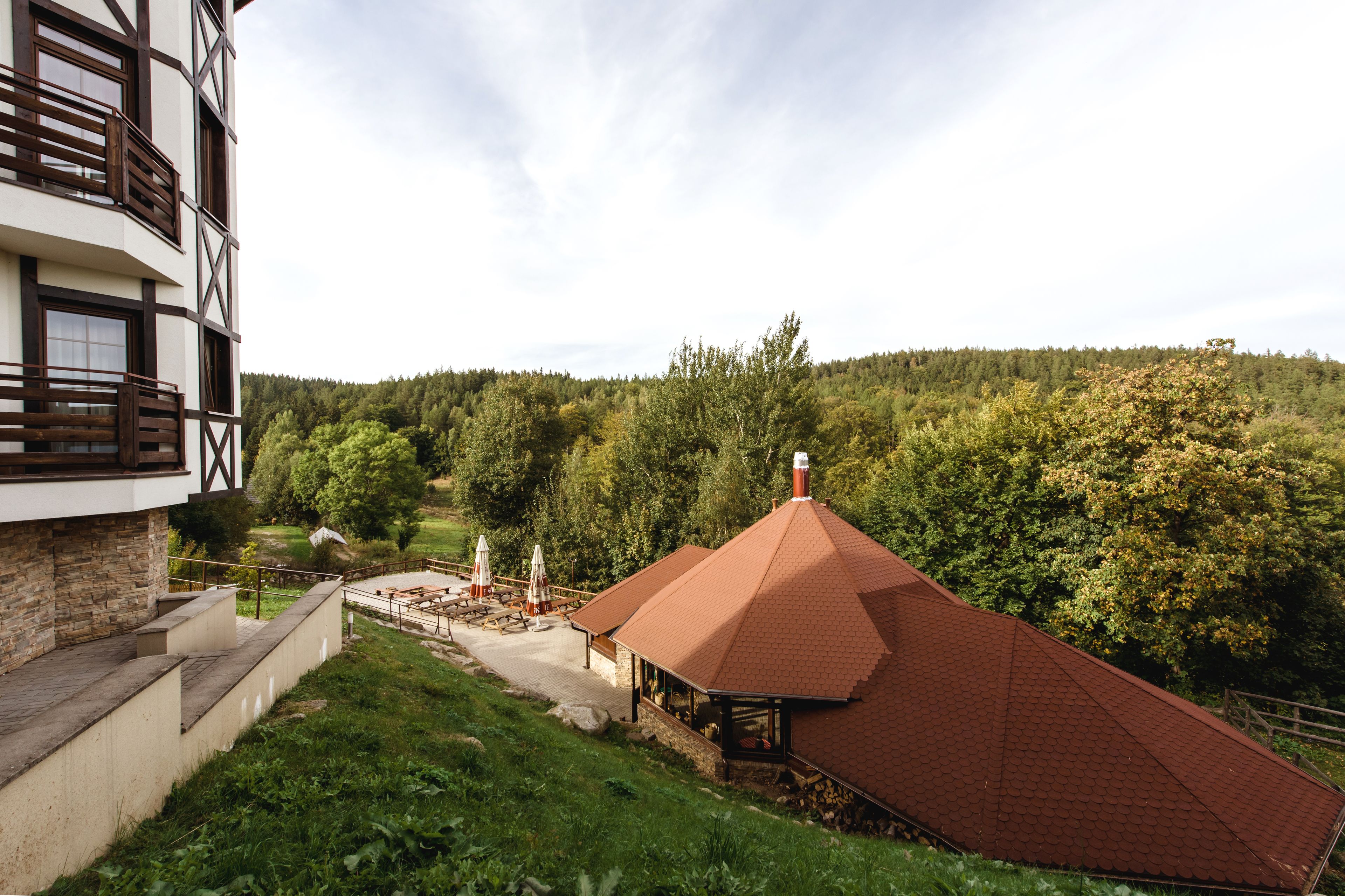 Een gebouw met een gevel van natuursteen en een structuur met een rood dak, gelegen in een groen landschap.